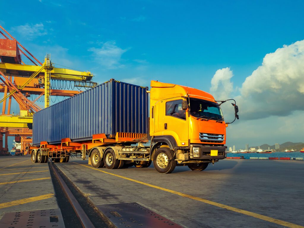 Caminhão transportando contêiner em terminal portuário ligado ao comércio exterior entre Mercosul e União Europeia.