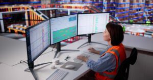Profissional monitorando indicadores e sistemas logísticos em operação automatizada.